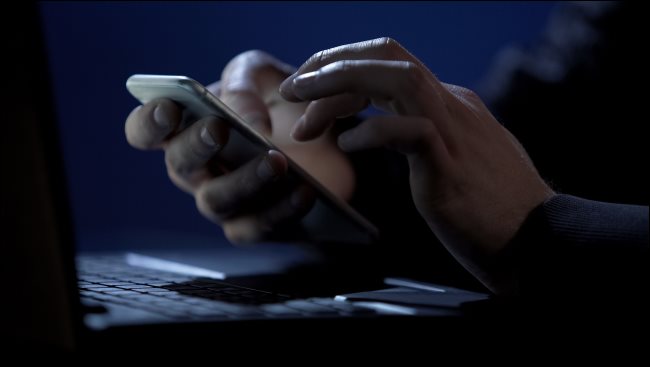 Hand holding a smartphone in a dark room.