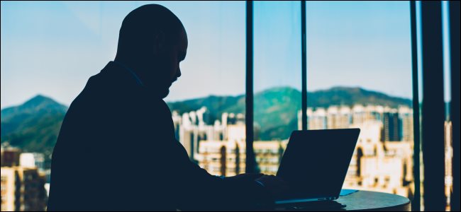 A silhouette of a man browsing on a laptop.