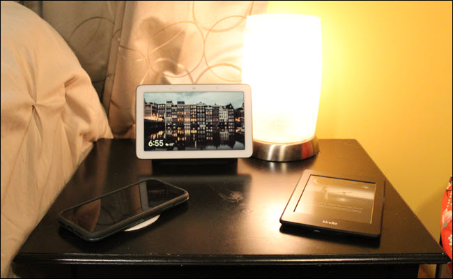 Nest Hub, Kindle, and iPhone on a nghtstand.