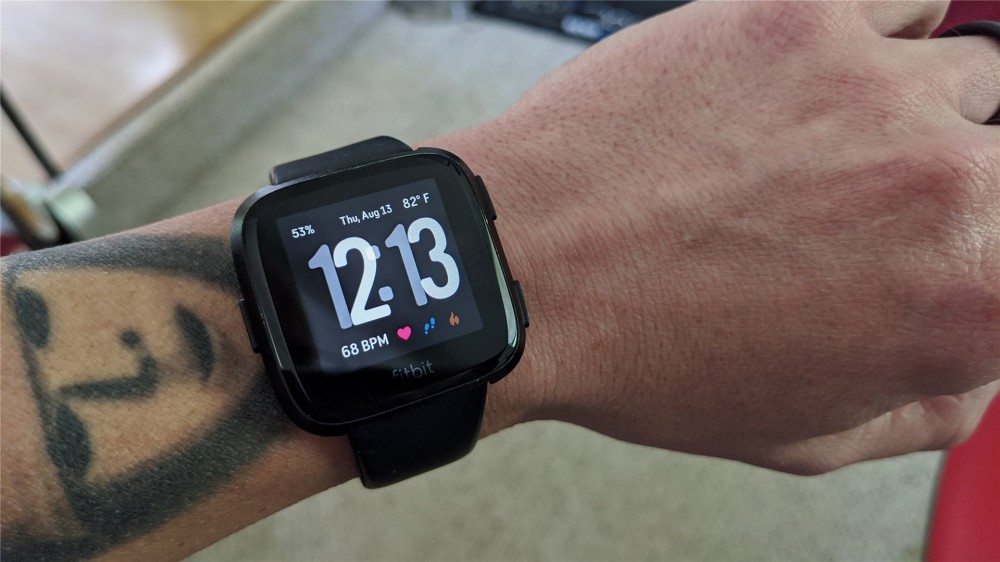 A fitbit versa showing time, weather, heart rate, and all other sorts of info