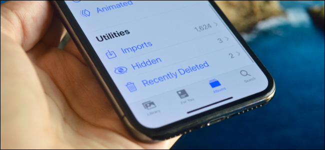 Someone holding an iPhone showing the "Hidden" folder under "Utilities."