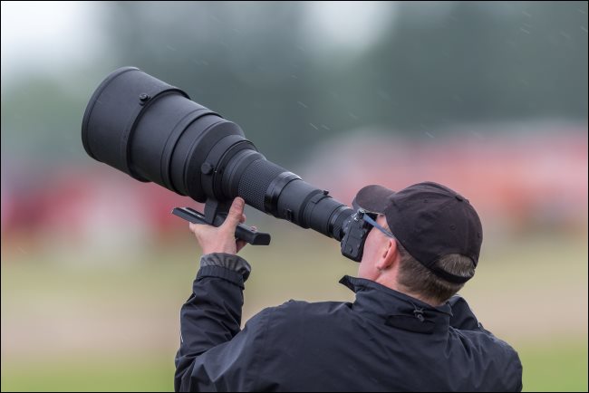 A photographer using a huge telephoto lens.
