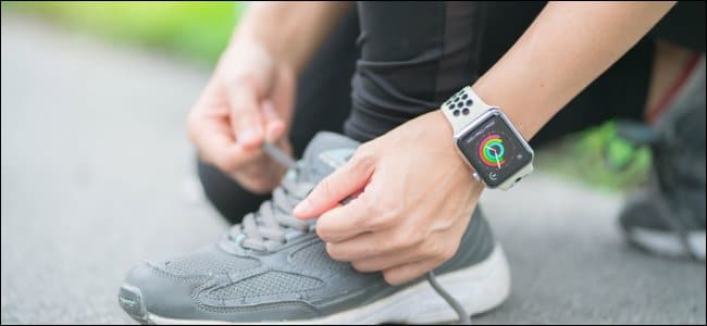 A woman tying her shoelaces while wearing an Apple Watch.